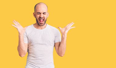 Gündelik tişört giyen genç yakışıklı adam başarı için deli ve çılgınlığı kutluyor kollarını kaldırmış ve gözlerini kapatmış heyecanla bağırıyor. Kazanan konsept 