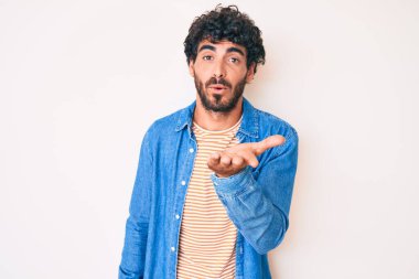 Kıvırcık saçlı yakışıklı genç adam ve sıradan kot ceket giyen ayı kameraya bakıp havada öpücükler savuruyor güzel ve seksi. aşk ifadesi. 