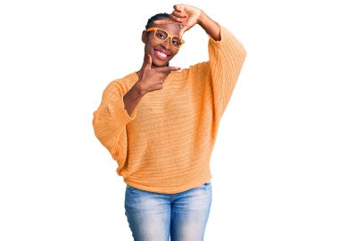 Gündelik kıyafetler ve gözlük takan, gülümseyen, elleri ve parmakları mutlu yüzlü genç Afro-Amerikan kadın. yaratıcılık ve fotoğrafçılık kavramı. 
