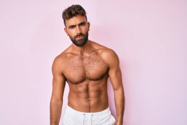 Genç İspanyol adam üstsüz, kuşkucu ve gergin duruyor, sorun yüzünden surat asıyor. negatif kişi. 