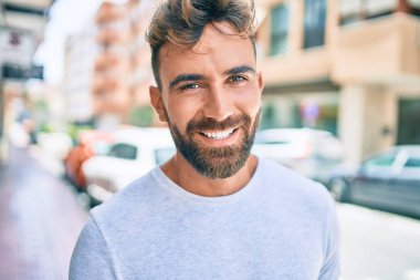 Genç İspanyol adam gülümseyerek şehirde mutlu bir şekilde yürüyor.