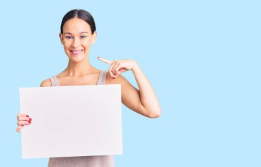 Güzel esmer, boş pankart tutan genç bir kadın mutlu ve gururlu bir kendini işaret ediyor. 