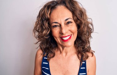 Orta yaşlı, esmer, çizgili tişört giyen güzel bir kadın beyaz arka planda mutlu ve havalı bir gülümsemeyle dikiliyor. Şanslı kişi..