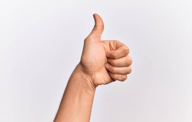 Beyaz arka planda parmaklarını gösteren beyaz tenli bir gencin eli başarılı bir onay hareketi yapıyor. Başparmak işareti, onay ve olumlu bir sembol ile.