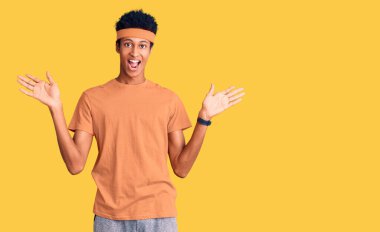 Afro-Amerikalı genç adam spor giyerek zaferi mutlu bir gülümsemeyle kutluyor ve kazanan yüz ifadesi kaldırıyor. 