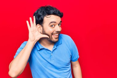 Gündelik kıyafetler giyen, ağzı kulaklarında gülümseyen, dedikoduları ve dedikoduları dinleyen genç İspanyol bir adam. Sağırlık kavramı. 