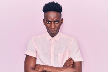 Gündelik kıyafetler giyen, kuşkucu ve gergin genç Afro-Amerikalı bir adam. Yüzünde çapraz kollarla onaylamayan bir ifade var. negatif kişi. 