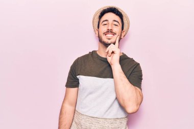 Gündelik giysiler giyen genç İspanyol adam kameraya kollarını kavuşturup çenesine dokunarak gülümsüyor. Olumlu düşünmek. 