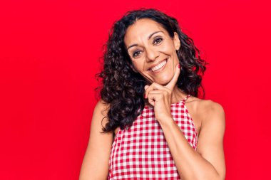 Orta yaşlı, kolsuz tişört giyen güzel bir kadın kameraya kolları çapraz ve çenesi açık gülümsüyor. Olumlu düşünmek. 