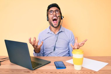 Çağrı merkezindeki operatör kulaklığı takmış genç İspanyol adam sinirli bir şekilde bağırıyor ve agresif bir ifade ve kolla bağırıyor. hüsran kavramı. 