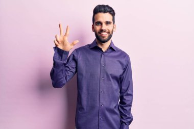 Sakallı, sıradan tişörtlü genç ve yakışıklı bir adam üç numaralı parmaklarıyla onu gösterirken kendinden emin ve mutlu bir şekilde gülümsüyor.. 