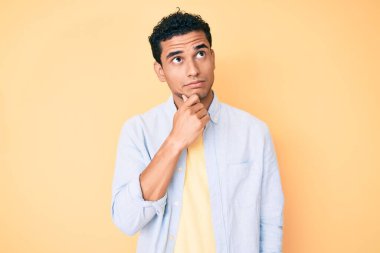 Sarı arka planda duran yakışıklı İspanyol bir adam parmak çenesinde şüpheye yoğunlaşmıştı. 