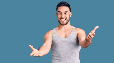 Mayo ve kolsuz tişört giyen genç yakışıklı adam gülümseyen, yardım eli uzatan ve kabul gören biri.. 