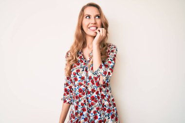 Sarışın, yaz elbisesi giyen, elleri ağızda, tırnaklarını yerken gergin ve gergin görünen beyaz bir kadın. anksiyete. 