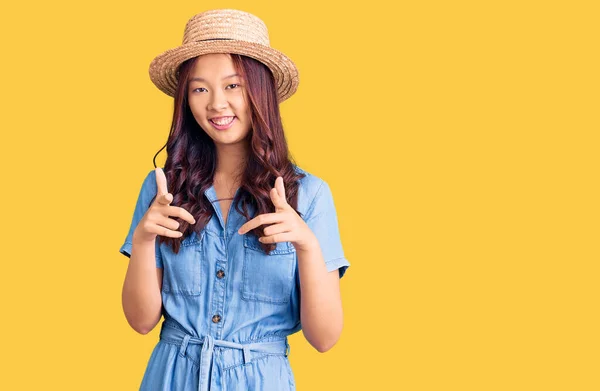 年轻美丽的中国姑娘头戴夏帽 手指对着相机 脸上洋溢着欢乐滑稽的表情 充沛的精力和活力 — 图库照片