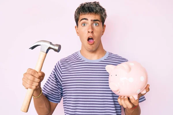 Jovem Homem Bonito Segurando Banco Porquinho Martelo Com Medo Chocado — Fotografia de Stock