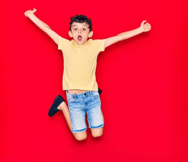 Adorable Niño Con Ropa Casual Saltando Sobre Fondo Rojo Aislado — Foto de Stock