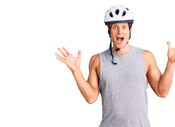 年轻英俊的男子戴着自行车头盔庆祝疯狂和惊奇的成功 举臂和睁开眼睛尖叫兴奋 获奖者概念 — 图库照片