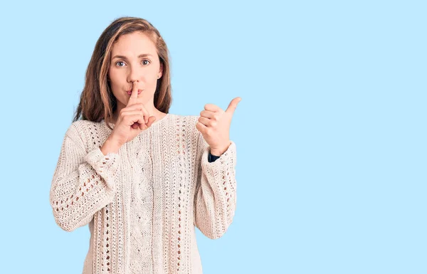 若い美しいブロンドの女性は サイドに手で指して唇に指で静かになるように求めるカジュアルなセーターを着ています 沈黙と秘密の概念 — ストック写真