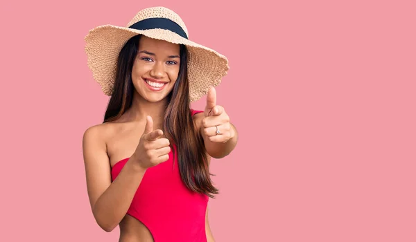 年轻美丽的缎子女孩穿着泳衣 戴着夏帽 手指着相机 脸上带着快乐和滑稽的表情 充沛的精力和活力 — 图库照片