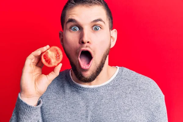 Joven Hombre Guapo Sosteniendo Rebanada Tomate Asustado Sorprendido Con Boca — Foto de Stock