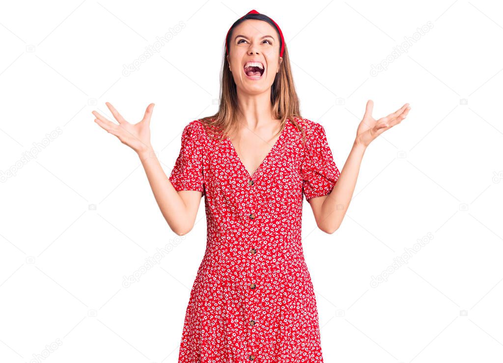 Young beautiful girl wearing dress and diadem crazy and mad shouting and yelling with aggressive expression and arms raised. frustration concept. 