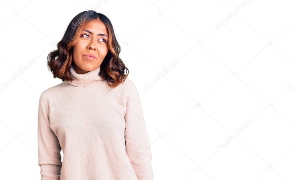 Young beautiful mixed race woman wearing winter turtleneck sweater smiling looking to the side and staring away thinking. 
