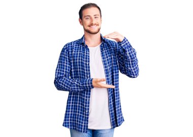 Genç, yakışıklı, beyaz, sıradan kıyafetler giyen, elleri büyük ve büyük bir işaret gösteren, ölçü sembolü olan bir adam. Kameraya bakıp gülümsüyor. ölçüm kavramı. 