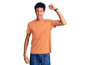 Genç, Afro-Amerikan bir adam, günlük kıyafetler giyiyor kızgın ve kızgın. Öfkeyle bağırırken yumruğunu kaldırıyor. öfke ve agresif konsept. 