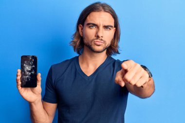 Elinde kırık akıllı telefon tutan yakışıklı bir adam kamerayı işaret eden kırık bir ekran gösteriyor ve sen kendine güvenen ciddi bir hareket yapıyorsun. 