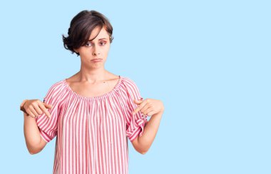 Kısa saçlı, günlük giysiler giyen üzgün ve üzgün görünen, yönünü parmaklarıyla gösteren mutsuz ve depresif bir kadın.. 