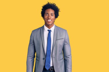 Afro saçlı yakışıklı Afro-Amerikan adam mutlu ve havalı bir gülüşü olan iş ceketi giyiyor. şanslı kişi. 