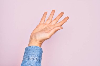 İzole edilmiş pembe arka plan üzerinde parmaklarını gösteren beyaz bir genç adam. Avuç içi açık bir şekilde yardım ve desteğe uzanıyor.