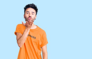 Üzerinde mutluluk mesajı olan tişört giyen genç İspanyol bir adam kameraya bakıp havada öpüşüyor ve çok güzel ve seksi oluyor. aşk ifadesi. 