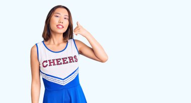 Genç, güzel Çinli kız amigo üniforması giyip gülümsüyor telefonla el ve parmak hareketleri yapıyor telefonda konuşuyor gibi. iletişim kavramları. 