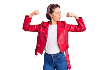 Kırmızı deri ceket giyen genç ve güzel bir kadın gururla gülümseyen kol kaslarını gösteriyor. fitness konsepti. 