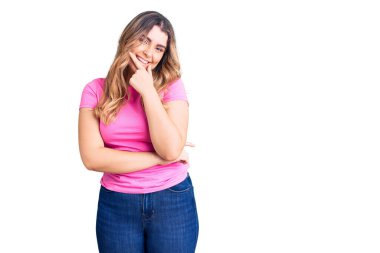 Spor kıyafetleri giyen beyaz bir kadın kameraya kendinden emin bir şekilde bakıyor kollarını kavuşturmuş ve çenesini kaldırmış gülümsüyor. Olumlu düşünmek. 