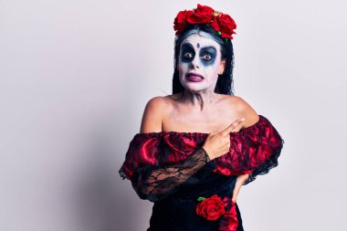 Meksika makyajlı genç bir kadın endişeli ve endişeli bir ifadeye işaret ediyor. 