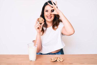 Genç, güzel esmer kadın bir bardak taze süt ve kurabiyelerle gülümsüyor. 