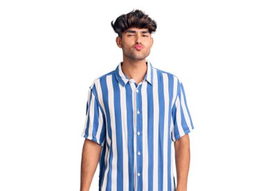 Latin asıllı genç bir adam, günlük giysiler içinde kameraya bakıyor ve güzel ve seksi bir şekilde havadan öpücük yolluyor. aşk ifadesi. 