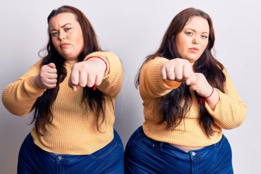 Genç ve cüsseli ikizler gündelik kıyafetler giyip dövüşmek için yumruklarını yumrukluyor agresif ve öfkeli saldırılar, tehdit ve şiddet. 