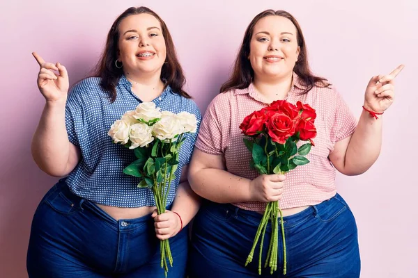 Çiçek tutan genç ve cüsseli ikizler mutlu bir şekilde elleri ve parmakları kenarda gezdiriyorlar. 