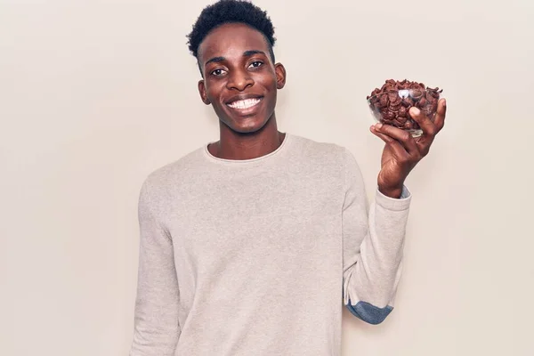 年轻的非洲裔美国人拿着巧克力麦片 面带微笑地站在那里 面带微笑 露出自信的笑容 露出牙齿 — 图库照片