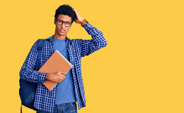 Young African American Man Wearing Student Backpack Holding Book Confuse — Stock Photo, Image