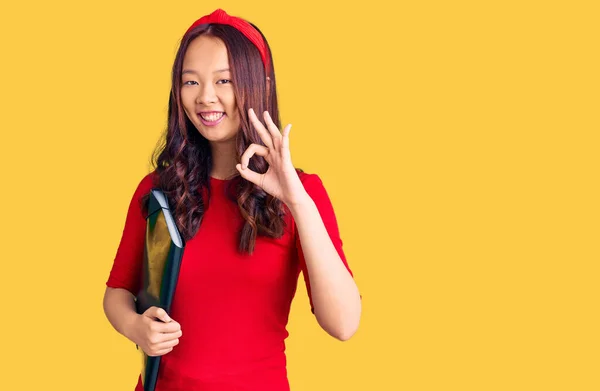 年轻美丽的中国女孩 身穿学生服 手握手签 微笑友善的手势 是极好的象征 — 图库照片