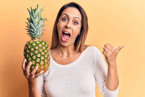 Jovem Mulher Bonita Segurando Abacaxi Apontando Polegar Até Lado Sorrindo — Fotografia de Stock