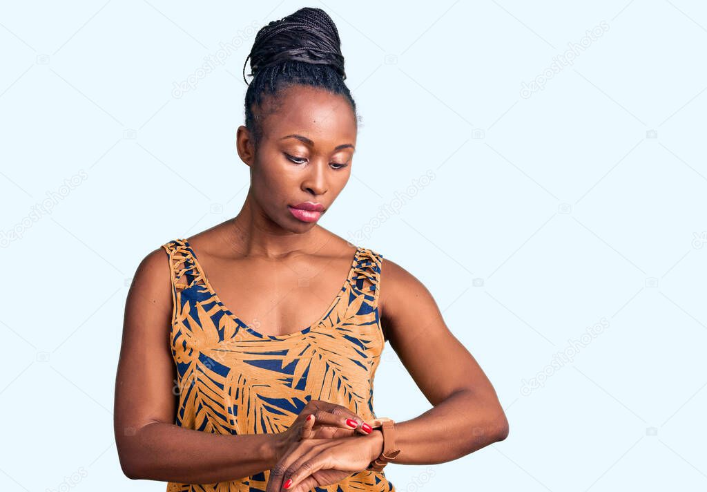 Young african american woman wearing casual clothes checking the time on wrist watch, relaxed and confident 