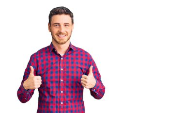 Ayılı yakışıklı genç adam, günlük tişört giyer, başarı işareti yapar, elleriyle olumlu jest yapar, gülümser ve mutlu olur. Neşeli ifade ve kazanan jest. 