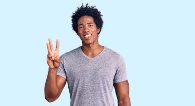 Yakışıklı, Afro saçlı, sıradan giyinmiş, üç numarayı işaret eden, kendinden emin ve mutlu gülümseyen Afro-Amerikan adam.. 