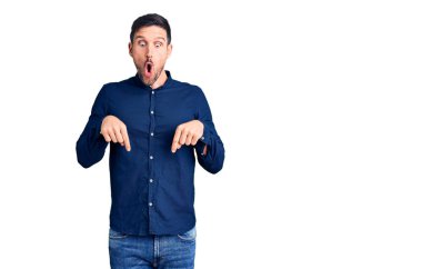 Genç, yakışıklı, rahat gömlekler giyen, parmaklarını gösterip reklamını yapan, şaşırmış ve ağzı açık genç bir adam. 